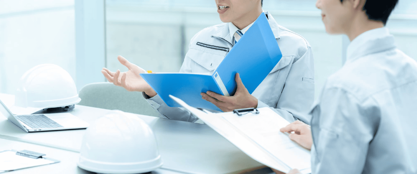 打ち合わせをする作業着のスタッフ